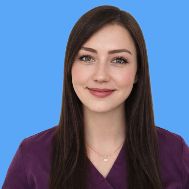 Frau mit langen, dunklen Haaren lächelt, trägt scrubs in lila. Hintergrund beige.