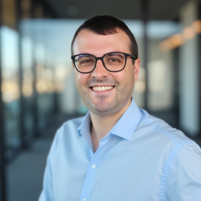 Lächelnder Mann mit Brille in einem modernen Bürogebäude.