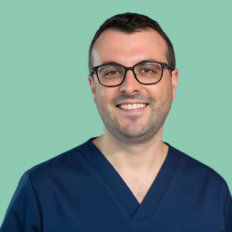 Lächelnder Mann in medizinischer Kleidung vor grünem Hintergrund.