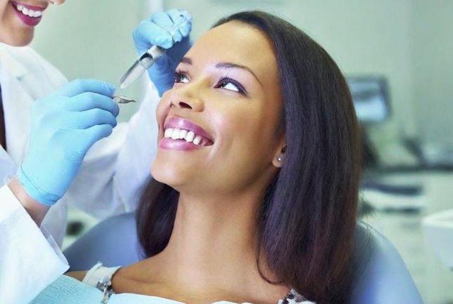 Zahnarzt besucht: Frau lächelt während einer Behandlung.